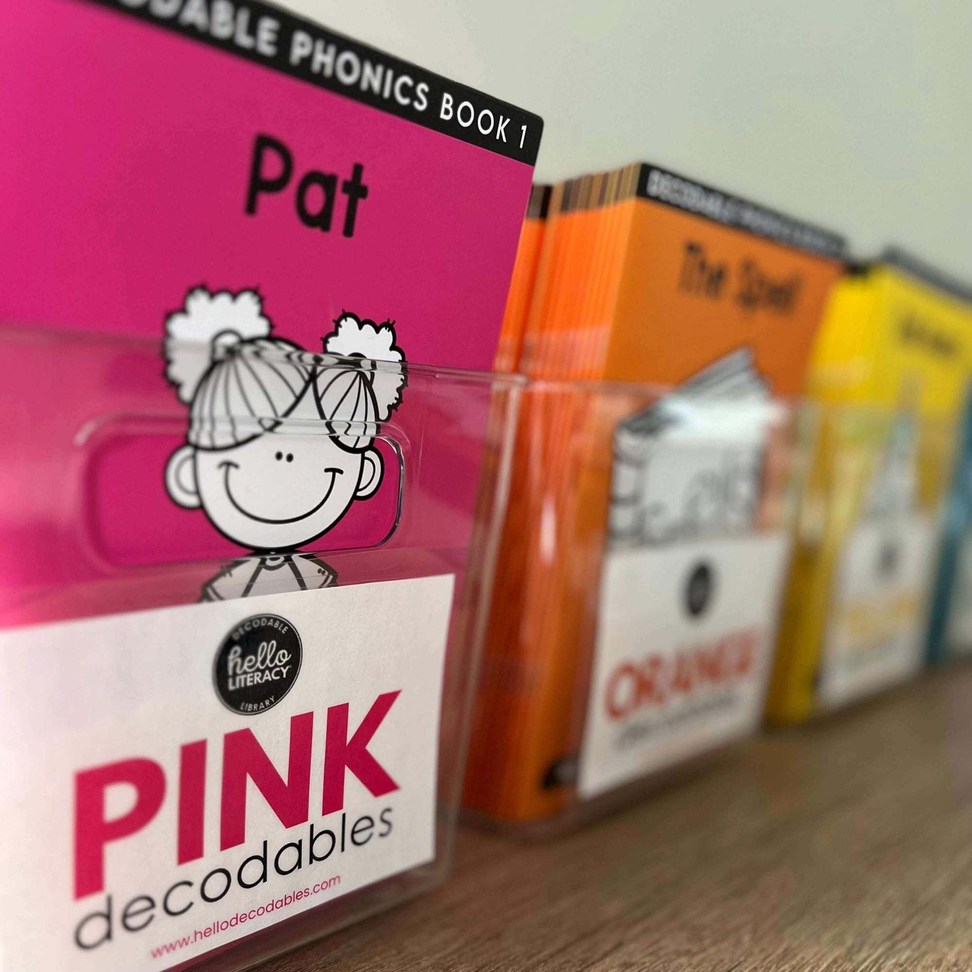 Decodable books in plastic bins with labels on the front of each bin, like Pink Decodables on the front of the pink decodables bin.